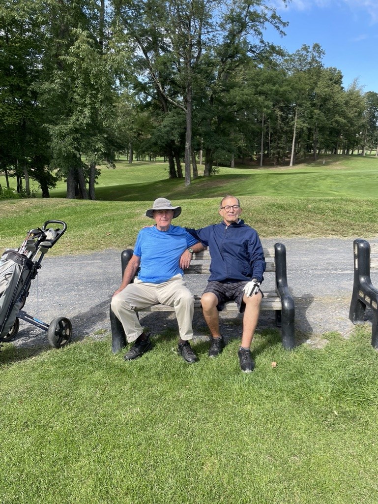 Younus Samadzada seated on a bench with a golfing companion